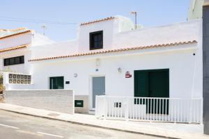 a white house with black doors on a street at Casa Iraría in Poris de Abona