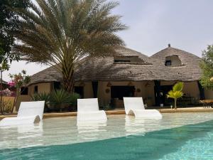 a resort with white chairs and a swimming pool at Adjana chambres d'Hôtes in Ngaring
