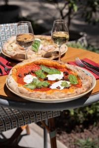 two pizzas sitting on a table with glasses of wine at Holiday Inn Nice by IHG in Nice