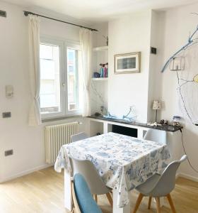 a white dining room with a table and chairs at Casa La Marina a Marina di Cecina by Zoom In Earth in Marina di Cecina
