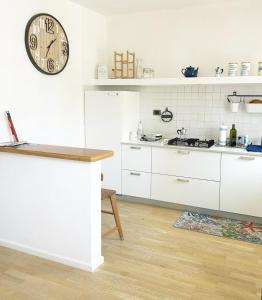 a kitchen with white cabinets and a clock on the wall at Casa La Marina a Marina di Cecina by Zoom In Earth in Marina di Cecina