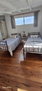 two beds in a room with wooden floors and windows at Ana home's in Mar del Plata