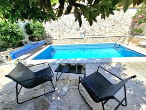 two chairs and a table next to a swimming pool at Villa Tina in Ploče