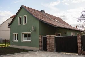 a green house with a fence in front of it at Ferienhaus zum Johannisthal in Hosena