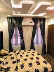 イバダンにあるAM Apartmentsのベッドルーム1室(ベッド1台、白黒の掛け布団付) +8枚の写真