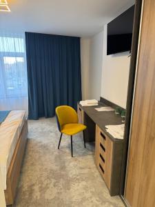a bedroom with a desk and a yellow chair at HRADBY hotel a restaurace in Uničov