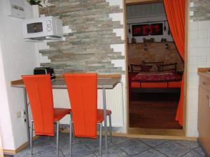 eine Küche mit orangefarbenen Barhockern und ein Schlafzimmer in der Unterkunft Wohnung in LübbenauSpreewald mit Garten, Terrasse und Grill in Lübbenau