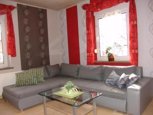 ein Wohnzimmer mit einem grauen Sofa und einem Glastisch in der Unterkunft Appartement in LübbenauSpreewald mit Garten und Grill in Lübbenau + 32 Fotos