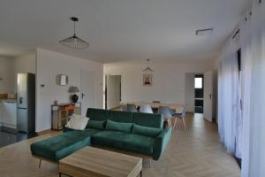 a living room with a green couch and a table at Maison Noé Climatisation individuelle par pièce proche du centre-ville in Ruoms