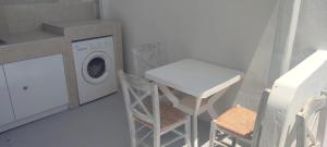 a laundry room with a washing machine and a chair at Filina's Room 1 in Maltezana