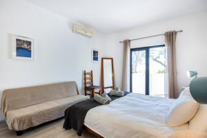 ein Schlafzimmer mit einem Bett und einer Couch in der Unterkunft CoolHouses Algarve, Luz, 3 Bed villa, 1 bed studio, heated pool & jacuzzi, sea views, Casa Pequena in Montinhos da Luz + 42 Fotos