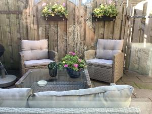 a patio with two chairs and a table with flowers at Zomerhuis Zwart in Egmond aan Zee