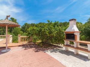 a brick patio with a fireplace and an umbrella at Holiday Home Lisboa by Interhome in Cala Murada