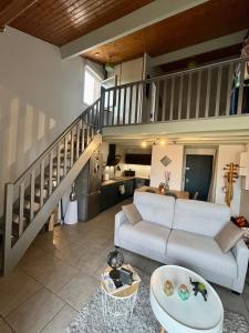 een woonkamer met een witte bank en een trap bij Le Donjon - Agréable T2 centre ville - parking gratuit 2 min - in Mont-de-Marsan