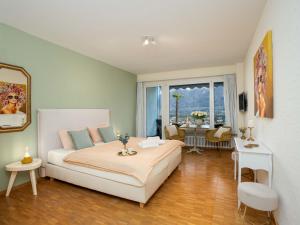 a bedroom with a large white bed and a table at Apartment Double Room Classic-5 by Interhome in Ascona +11 photos