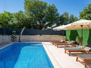 a swimming pool with two chairs and an umbrella at Holiday Home Domagoj by Interhome in Malinska