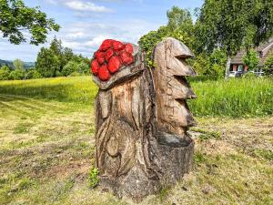 a wooden statue with a bunch of red flowers on it at Apartment Sonnenmatt App- 12 by Interhome in Höchenschwand