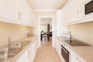 a kitchen with white cabinets and a sink and a table at Vale Do Lobo Resort in Vale do Lobo