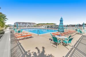 a pool with chairs and a table with a umbrella at Grande at Canal Pointe --- 37546 Worcester Dr. in Rehoboth Beach