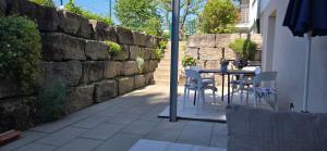 a patio with a table and chairs next to a stone wall at Ankerplatz in Lindau