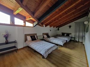 two beds in a room with wooden ceilings and wooden floors at Alojamientos Turísticos TURBON - Campo in Campo
