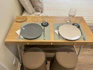 a wooden table with two plates and wine glasses at Studio Centre-ville in Libourne