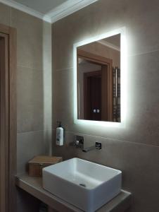 ein Badezimmer mit einem weißen Waschbecken und einem Spiegel in der Unterkunft Τhe Diamond in Néa Péramos