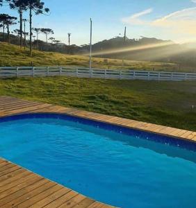 una piscina blu con un ponte di legno e una recinzione di Casa Oliva com piscina e 6 quartos a Rancho Queimado