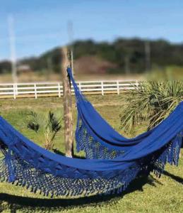 un'amaca blu in un campo vicino a una recinzione di Casa Oliva com piscina e 6 quartos a Rancho Queimado