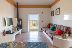 a living room with a couch and a tv at Vila Bita Agroturismo in Almodôvar
