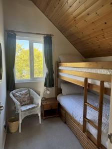 a bedroom with a bunk bed and a chair at Robin's Nest - Cotswold Lakeside Lodge - Spring Lake in South Cerney