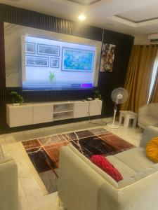 a living room with a large television and a couch at ADES Home in Lekki