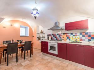 a kitchen with red cabinets and a table with chairs at Apartment Casa Derna by Interhome in Pietrabuona