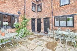 a patio with tables and chairs in front of a brick building at Host & Stay - Granary Barn in Fakenham +15 photos