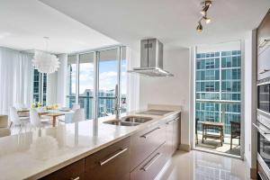 a kitchen with white counters and a dining room with a table at MVR - Designer Condo in Prime Brickell in Miami