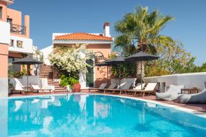 einen Pool mit Stühlen und Sonnenschirmen neben einem Haus in der Unterkunft Nisea Hotel Samos in Pythagoreio