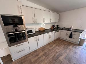 a large kitchen with white cabinets and a wooden floor at Eickhof Ferienzimmer No2 mit Bad, Parkplatz - Ferienhof Günter in Warnow +7 photos