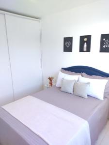 un letto bianco con cuscini bianchi in una camera da letto di Praia canavieiras a Florianópolis