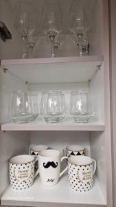 a shelf with cups and glasses on it at Antreas cosy apartment in Paralio Astros +33 photos
