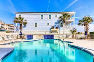 a swimming pool in front of a house with palm trees at Blockade Runner in Myrtle Beach