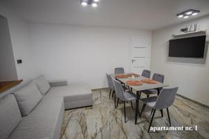 un soggiorno con un divano e un tavolo con sedie di Apartamenty Katarzyna a Święta Katarzyna