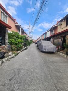 ein Auto mit einer Abdeckung, das am Straßenrand geparkt ist in der Unterkunft Cathy's Transient House in Bacoor