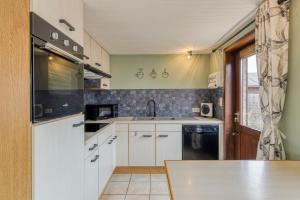 a kitchen with white cabinets and a sink at Sun Sea vakantiehuis in Middelkerke +10 photos