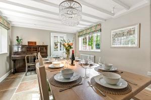 ein Esszimmer mit einem Tisch mit Stühlen und einem Kronleuchter in der Unterkunft Honeypot cottage in Lower Assendon