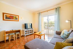 a living room with a couch and a tv at Jardins Vale de Parra in Albufeira