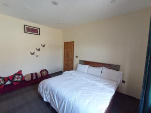 a bedroom with a large bed with white sheets at Hunza Ray's guest house in Dargai