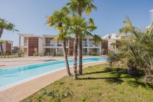 ein Swimmingpool mit Palmen vor einem Haus in der Unterkunft Wave Island H2 in Lido di Jesolo