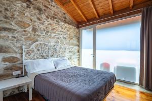 una camera da letto con un letto e un muro di pietra di Casa Silverio a Monforte de Lemos Altre 16 foto