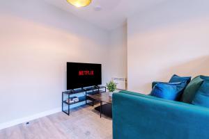 a living room with a blue couch and a tv at Elysée Suites - Modern 1 Bed Flat in Southport in Southport +29 photos