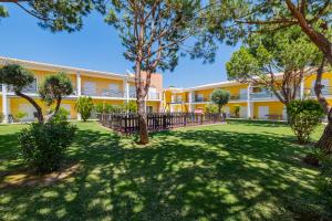 a large yellow building with trees in the yard at Pool&Beach in Encosta de São José in Albufeira